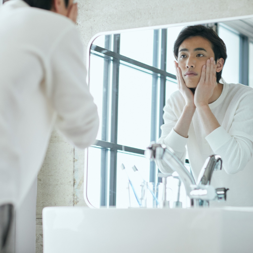 男性鏡の前洗顔後