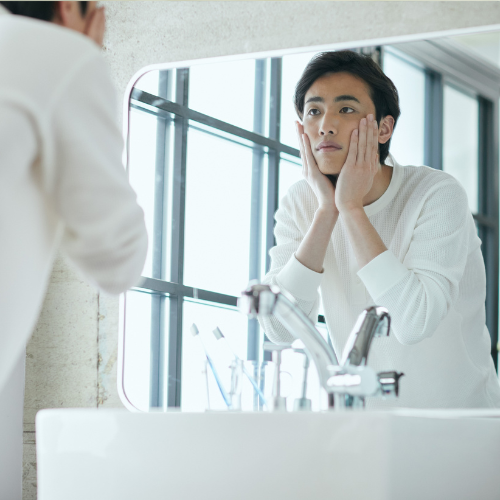 鏡の前で肌を確認する男性